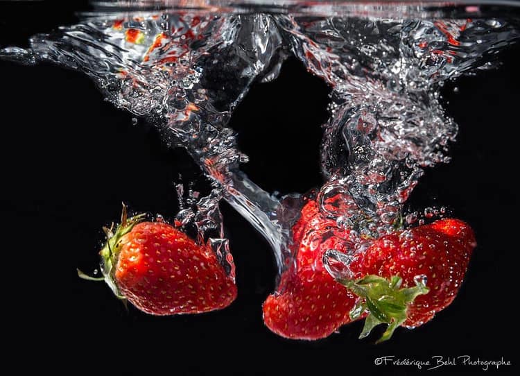 La chute des fraises dans l'eau prise en haute vitesse
